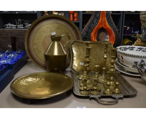 A group of brass candlesticks, largest H21.5cm, sold together with a brass pitcher and various trays, ( 15 ).