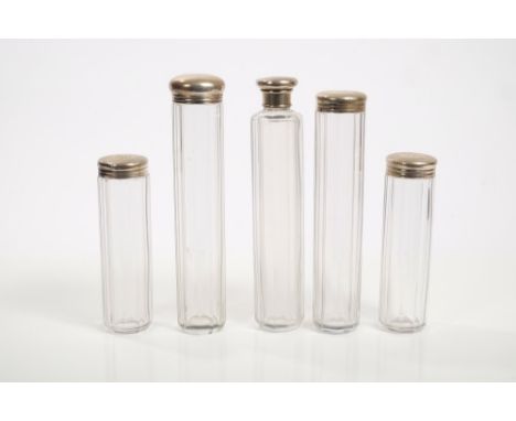 Four Victorian decagonal glass toilet bottles with silver engine-turned and monogrammed tops (London 1873), together with one