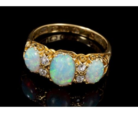 Edwardian 18ct gold opal and diamond ring, the three oval cabochon opals interspaced by four old cut diamonds, in carved gold