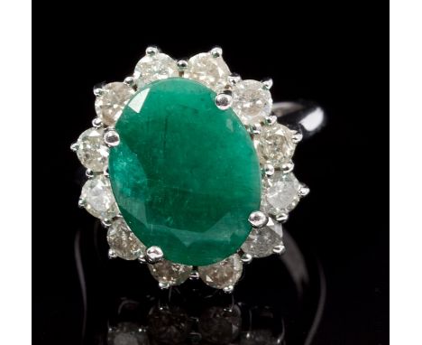 Emerald and diamond cluster ring, the oval mixed cut emerald measuring approximately 15.43mm x 11.89mm, surrounded by twelve 