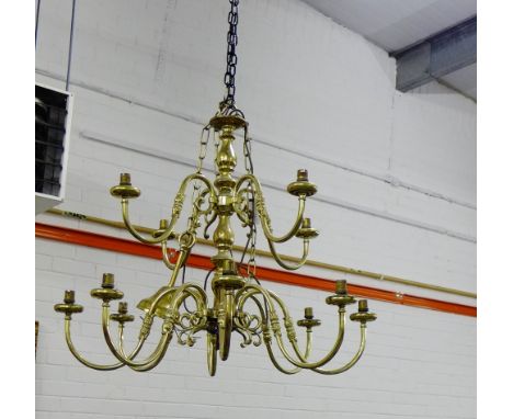 A Dutch style brass light fitting with four scroll arms to the upper tier and eight longer branches to the lower tier 