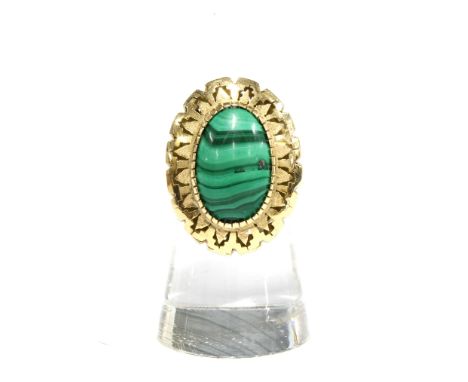 Polished malachite cabochon dress ring in an unmarked yellow metal surround on an unmarked band 