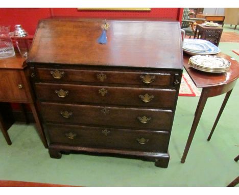 A George III oak bureau the fitted interior over four long graduating drawers with oak linings on bracket feet (fall with wor