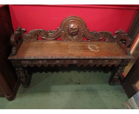 A Jacobean style oak carved bench/settle with mask and foliate design 