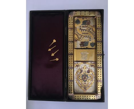 A cribbage board and four pins, silver and gold finished with playing cards motif, in leather case. IMPORTANT: Online viewing