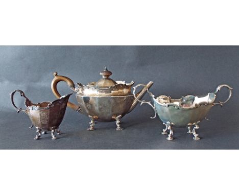 Late Victorian silver three piece tea service with raised scrolled cartouche rims and faceted bowls upon cabriole shell feet,