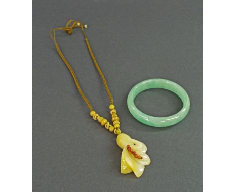 Chinese circular pale jade bangle, 48.1gm, outer 2.75" diameter; together with a hardstone carved pendant on an entwined neck