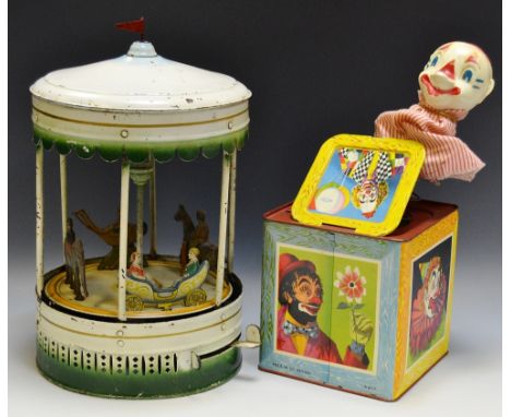 A Gunthermann clockwork tin plate carousel, creamy white body, red flag crest above a blue ring topper roof, with deep green 
