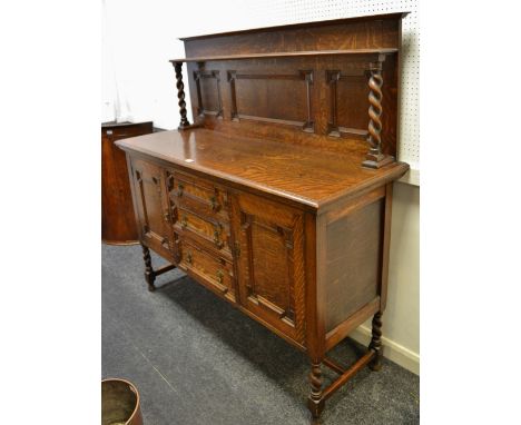 An oak sideboard, shelf  and barley twist supports to panelled gallery, oversailing top, three graduated drawers flanked by p