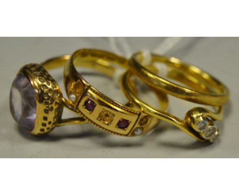 A 15ct gold gypsy ring; a 9ct gold band; a gold coloured metal diamond trilogy ring set on a twist; another set with a purple