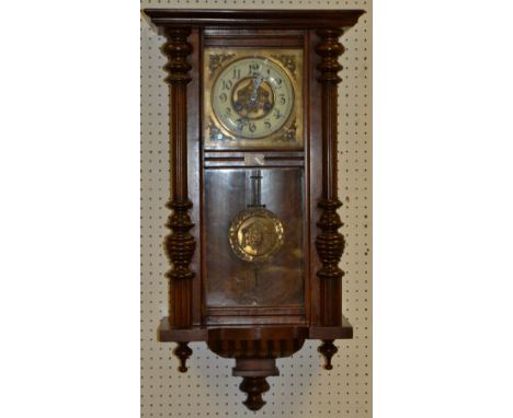 A walnut Vienna wall clock, glazed door flanked by turned pilasters, brass face, enamelled chapter ring, Roman numerals