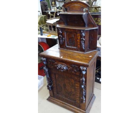 A ornate carved Continental oak side cabinet, raised cupboard and shelf back, with an arched panel cupboard under, and carved