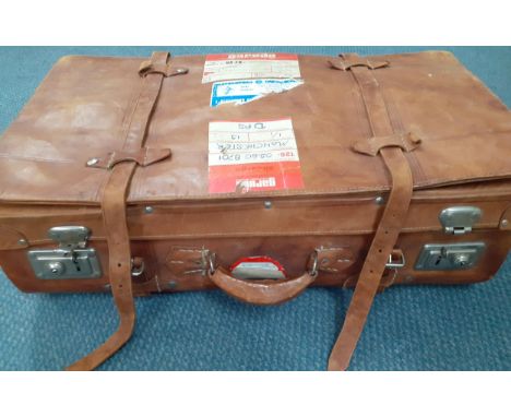 A vintage brown leather suitcase having a Batik lining and Indonesian Airways stickers to the exterior and silver tone hardwa