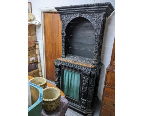 A 19th century ebonized and parquetry carved wooden side cabinet, carved pediment over an arched open top with shelf space (s