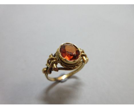 A single stone hessonite garnet ring, the oval cut burnt orange colour hessonite crimp collet set to a ropetwist mount and ba