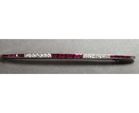 A French Art Déco diamond and synthetic ruby bar brooch set in platinum, the long narrow bar channel set with a tapering line