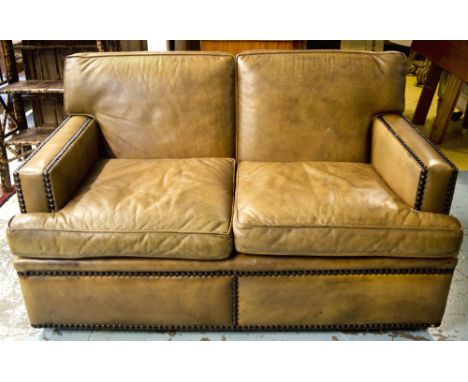 SOFA, studded tan leather with two seat cushions and castors, 144cm W x 92cm D.