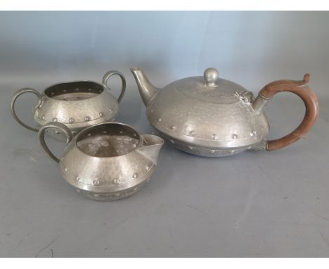 An Arts and Crafts style pewter tea service of tea pot, milk and twin handled sugar - in moderate condition with a few surfac