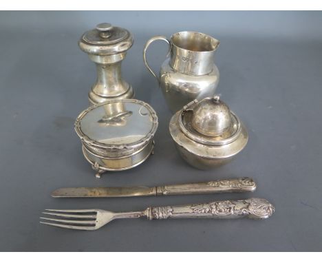 A silver hallmarked knife and fork, a pepper mill, a Victorian silver cream jug dated 1889-90, a small silver hallmarked circ