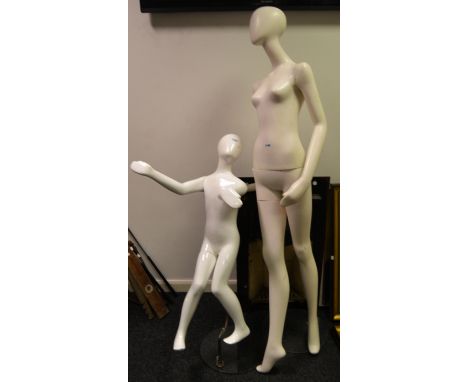 A shop display mannequin of a female form; another of a child, on stand