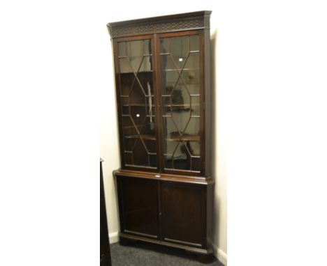 An early 20th century free standing corner unit , carved frieze, astral glazed doors enclosing three shaped shelves, projecti