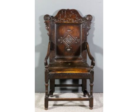 A late 17th Century panelled oak armchair with shaped crest rail carved with the initials "HS" and dated 1692, the panel carv