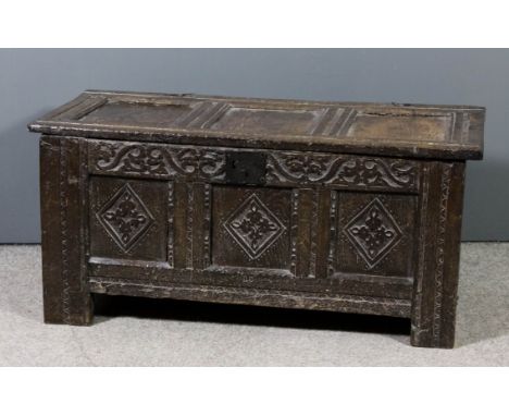 A 17th Century panelled oak coffer with three fielded panel lid, the front carved with leaf scroll ornament and lozenge ornam