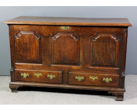 A mid 18th Century panelled oak mule chest, the plain lid with moulded edge, the front with three shaped and fielded panels a