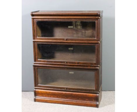 A Globe Wernicke oak three tier sectional bookcase, each tier enclosed by a rising glazed panel, and on plinth base, 34ins wi