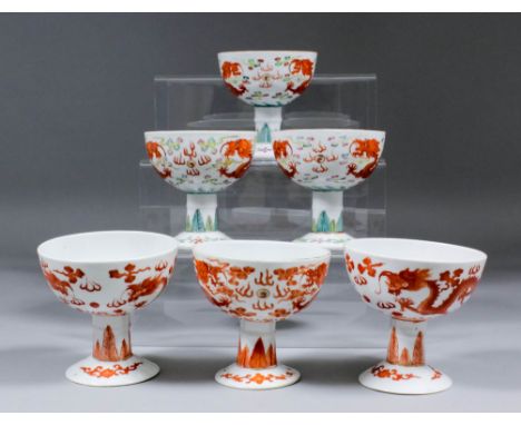 Three Chinese red and white porcelain circular stem cups each decorated with dragons chasing the sacred pearl, with leaf orna