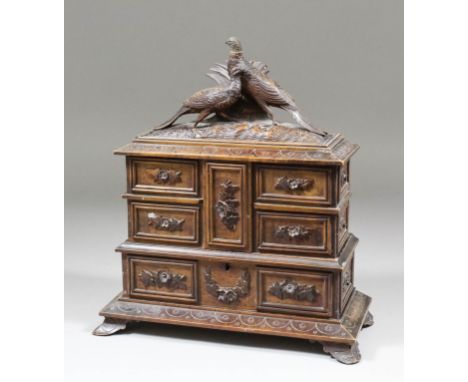 A 19th Century "Black Forest" carved wood jewellery cabinet, carved with swags of flowers, surmounted by two game birds, the 