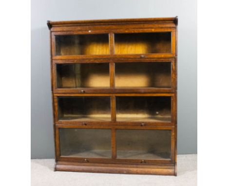 An oak four tier sectional bookcase in the "Globe Wernicke" manner, each tier enclosed by a rising glazed panel, and on plint