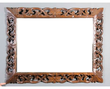 A late Victorian oak framed rectangular wall mirror, the frame boldly fretted and carved with floral and leaf scroll ornament