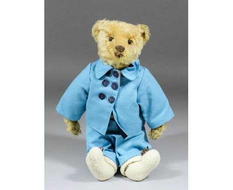 An early 20th Century Steiff blond mohair bear with button eyes, 13ins high, dressed in "The English Teddy Bear Company" jack