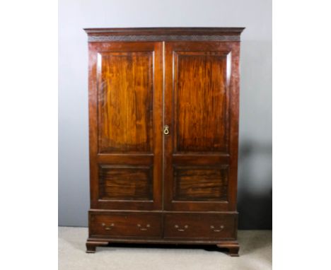 A mahogany wardrobe of Georgian design with moulded cornice enclosed by a pair of fielded panelled doors, fitted two drawers 