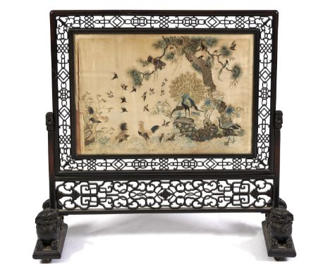 A Chinese hardwood firescreen, late 19th c, inset with a finely embroidered silk banner of fowl, including peafowl, hawk, fin