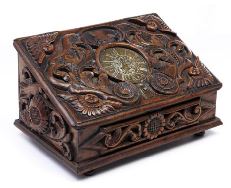 A Continental carved walnut box, the sloping lid set with an engraved brass clock dial with pierced hand connected to the cat