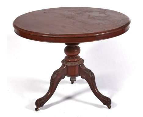 A Victorian mahogany breakfast table, the round tip-up top on spool and globe knop and leaf carved tripod, brass castors, 72c