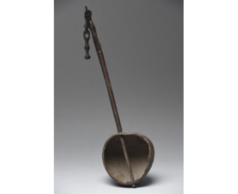 An Irian Jaya ladle Indonesia with a coconut shell bowl and a wood handle with a carved korvar figure and an integral chain e