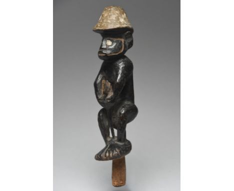 A Solomon Islands figure Melanesia probably a canoe ornament, the squatting figure wearing a conical cap with a recess to the