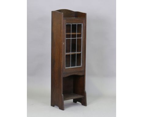 An Edwardian Arts and Crafts stained oak glazed bookcase by Liberty &amp; Co, the leaded glass door above an open shelf, heig