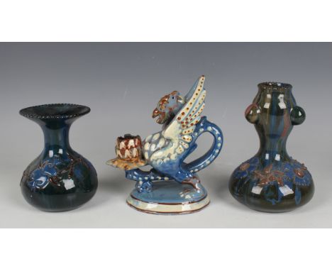 A C.H. Brannam pottery griffin chamberstick, circa 1899, the blue and cream glazed creature supporting a sconce on the end of