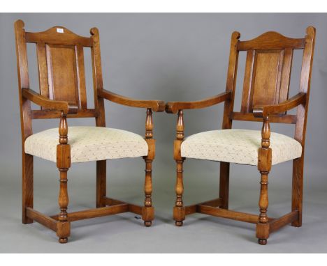 A set of eight modern Jacobean style oak panel back dining chairs with overstuffed seats, comprising two carvers, height 111c