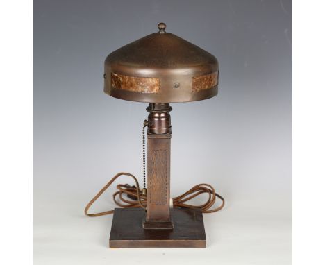 An early 20th century Arts and Crafts copper table lamp by Roycroft, the domed shade inset with four panels of mottled brown 