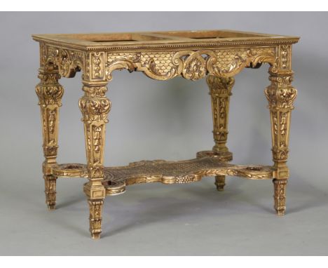 An early 20th century Continental carved giltwood lamp table base, the frame carved with scrolls and bellflowers, the underti