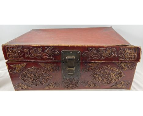 A vintage red leather trunk with Oriental floral &amp; character relief design to front &amp; sides. Drop metal handles to bo