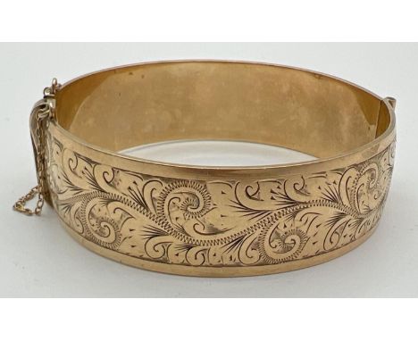 A vintage 9ct rolled gold bangle with safety chain and floral engraving to front. Makers mark and gold marks to inside of ban