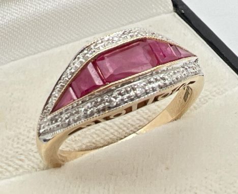 A 9ct gold Art Deco design diamond and ruby set dress ring by Luke Stockley, London. Central baguette cut ruby with a keyston