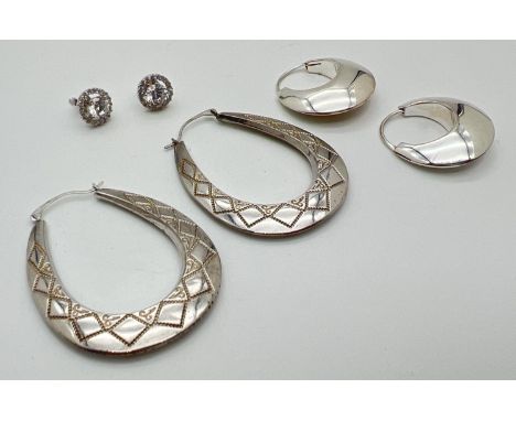 3 pairs of silver earrings. A stud style pair set with clear round cut stones, a pair of modern bubble style hoops and a pair