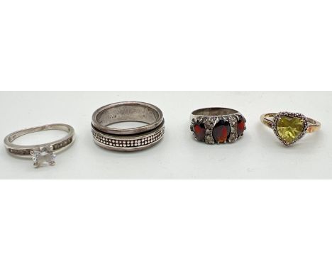 4 silver dress rings. A silver spinner band ring; a vintage garnet set eternity style ring; a heart cut yellow stone surround